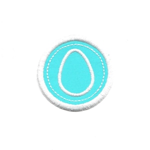 May include: A white felt patch with a blue felt egg shape inside. The egg shape has a white outline.