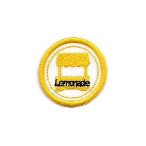 May include: Yellow embroidered patch with a white circle and a yellow lemonade stand inside. The words "Lemonade" are written in black below the stand.
