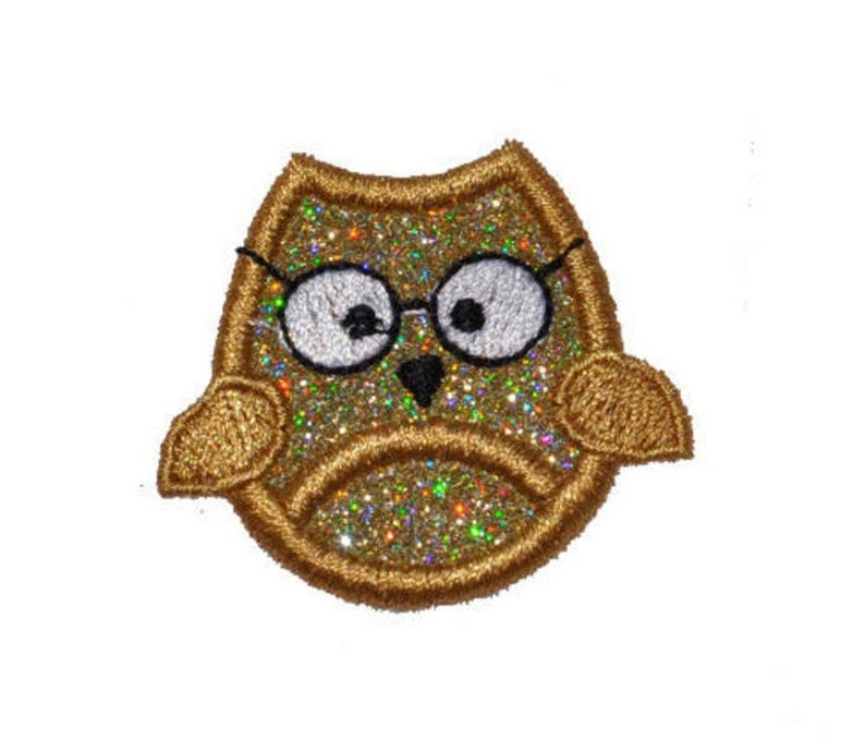 Puede incluir: B&uacute;ho de purpurina dorada con gafas negras, un bonito parche bordado.