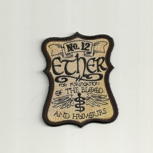 Puede incluir: Un parche bordado marrón y beige con el texto "No. 12 Ether for Purification of the Blood and Humours" en letras negras. El parche presenta un símbolo de caduceo alado.