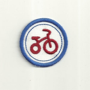 Op de afbeelding: Een geborduurd ontwerp van een fiets in rood op een witte achtergrond met een blauwe rand.