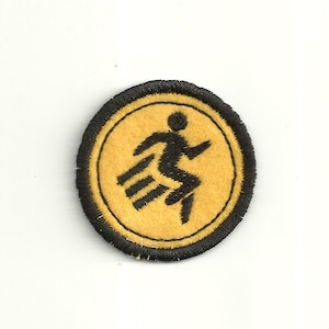 May include: A yellow and black embroidered patch with a running figure in the center.