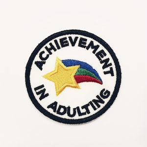 May include: An embroidered patch with a rainbow star and the text "Achievement in Adulting".