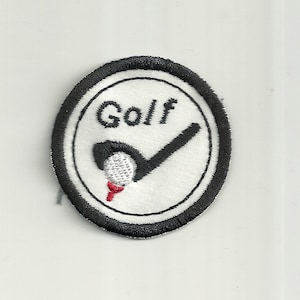 Pode incluir: Um remendo branco bordado com uma borda circular preta. O remendo apresenta um taco de golfe preto atingindo uma bola de golfe branca em um tee vermelho. A palavra "Golf" é bordada em preto acima do taco de golfe.