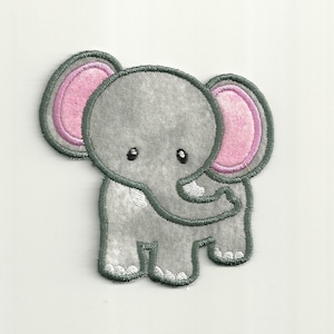 Op de afbeelding: Een grijze vilt applique van een olifant met roze oren en een witte omtrek. De olifant heeft een kleine slurf en staat op vier poten.