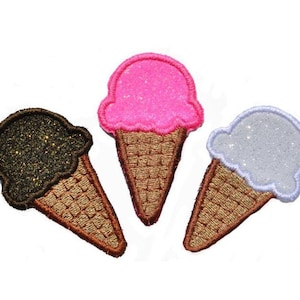 Puede incluir: Tres parches bordados de conos de helado. Uno es rosa, otro es blanco y otro es negro.