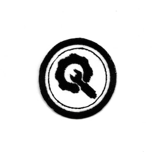 Könnte beinhalten: Schwarz-weiß gestickter Aufnäher mit einem stilisierten Buchstaben Q in einem Kreis.