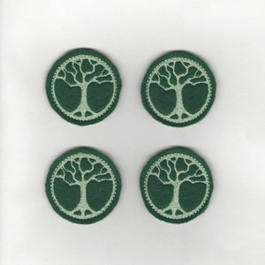 May include: Four green felt circles with a white embroidered tree of life design.