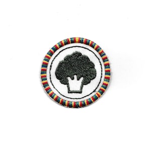 May include: A white embroidered patch with a green tree silhouette inside a circle. The circle has a red, yellow, blue, and green striped border.