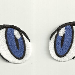May include: Two blue cartoon eyes with white pupils and black outlines. The eyes are embroidered on a white fabric.