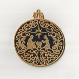 May include: A gold embroidered Christmas bauble with a dark blue background. The bauble features a nativity scene with the star of Bethlehem and a decorative floral design.