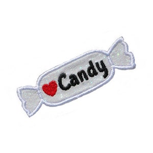 Könnte beinhalten: Weißer, bonbonförmiger Patch mit einem roten Herzen und dem Text "I Love Candy" in schwarzer Stickerei.