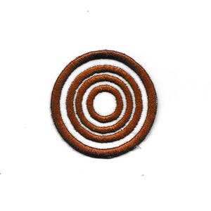 May include: A brown and white embroidered patch with a concentric circle design.