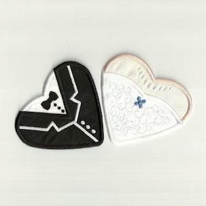 Puede incluir: Dos parches en forma de corazón, uno que representa un esmoquin con pajarita, el otro un vestido de novia con encaje y una cruz azul. Los parches son blancos, negros y beige, ideales para manualidades de boda.