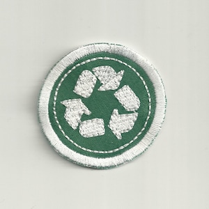 May include: Circular embroidered patch displaying the recycling symbol. The design features a green circle with a white recycling symbol at its centre, enclosed by a white border. The patch has a stitched edge and is designed to be sewn on.
