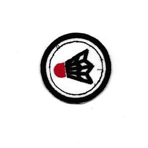 May include: A black and white embroidered patch featuring a red shuttlecock in the centre. The shuttlecock is surrounded by a white circle with a black border.