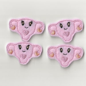 May include: Four pink felt patches with embroidered images of a uterus with a smiling face, hearts, and gold accents.