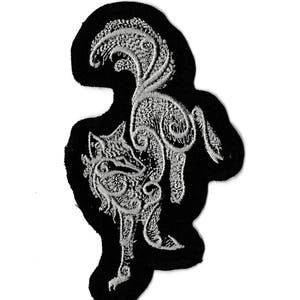 Op de afbeelding: Een zwarte geborduurde patch met een wit, gedetailleerd ontwerp van een haan. De haan staat op één poot met zijn staartveren omhoog.