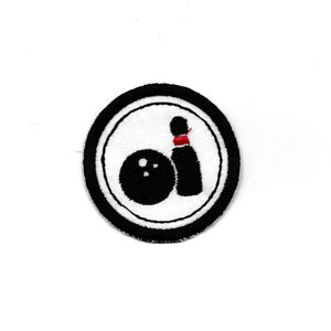 May include: Black and white embroidered patch of a bowling ball and pin in a circle with a black border.