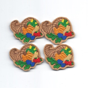 May include: Four brown felt appliques of a cornucopia filled with fall harvest items. The cornucopia is filled with pumpkins, corn, and red peppers. The cornucopia is decorated with green leaves and blue berries.