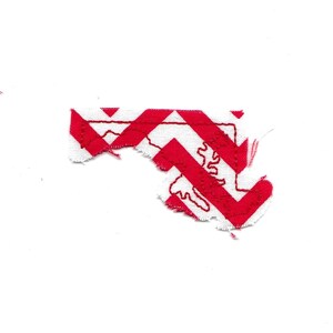 May include: A red and white fabric patch in the shape of the state of Maryland. The outline of the state is stitched in red thread.