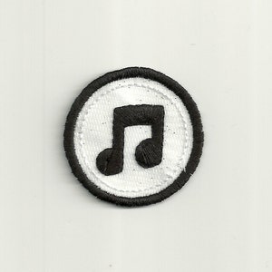 May include: A black and white embroidered patch with a musical note in the center. The patch is circular and has a black border.