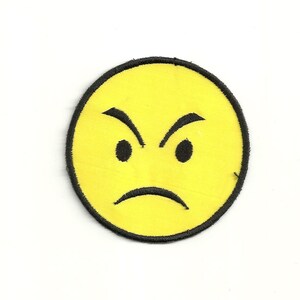 Peut inclure: Visage jaune souriant avec une bouche renfrognée et des sourcils froncés. Le visage est souligné de noir.