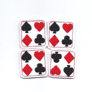 May include: Four white felt squares with red and black embroidered playing card suits. Each square has a different combination of the four suits: spades, hearts, diamonds, and clubs.