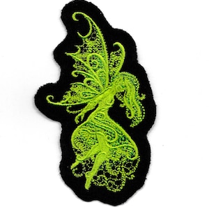 May include: Green embroidered fairy with wings and flowing hair on a black fabric patch.
