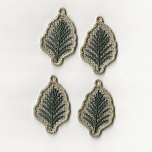 Op de afbeelding: Vier beige stoffen ornamenten met groene geborduurde bladeren. Elk ornament heeft een lus om op te hangen.