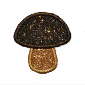 Könnte beinhalten: Ein schwarzer und goldener Glitzer-Pilz-Patch. Der Pilz hat eine abgerundete Kappe und einen kurzen Stiel.