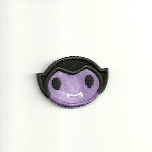 May include: Purple and black felt applique of a cartoon vampire with fangs.