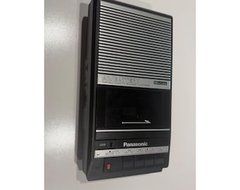 May include: A black and silver Panasonic portable cassette recorder featuring a Slim Line design, AC/Battery power options, and an auto stop function. The device includes a speaker grille, a cassette compartment, and control buttons.