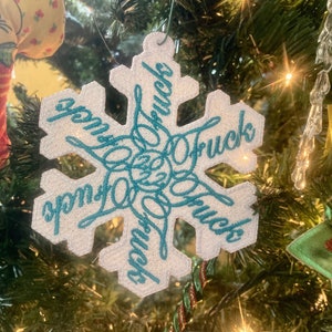 May include: White snowflake-shaped Christmas ornament with the words "Love Trucks" embroidered in teal blue.