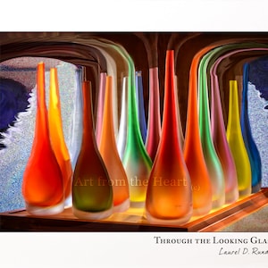 May include: A collection of colorful glass vases in various shades of red, orange, yellow, green, blue, and purple. The vases are arranged in a row on a wooden surface. The text "Art from the Heart" is visible in the image.