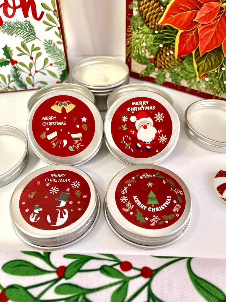 May include: Several small, round, silver tins with red labels displaying festive Christmas designs and the words "MERRY CHRISTMAS." The labels show bells, Santa Claus, snowmen, and Christmas trees. The tins contain white wax.