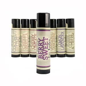 May include: A row of ten lip balm tubes with different flavors, including coconut lime, cherry vanilla, cherry lemonade, berry sweet, grapefruit tangerine, lemon lavender, and coffee and cream. The tubes are all black with white labels and are arranged in a row on a white background.