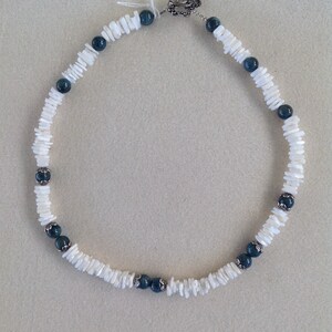 May include: A white shell and blue gemstone necklace with a silver clasp.