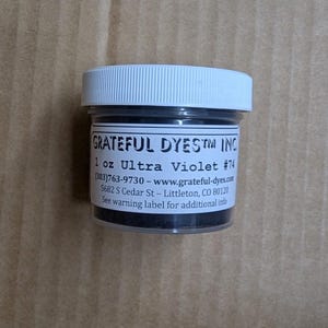 May include: A small jar of Ultra Violet #74 dye from Grateful Dyes Inc. The jar has a white lid and a label with product information. The jar contains 1 oz of dye.