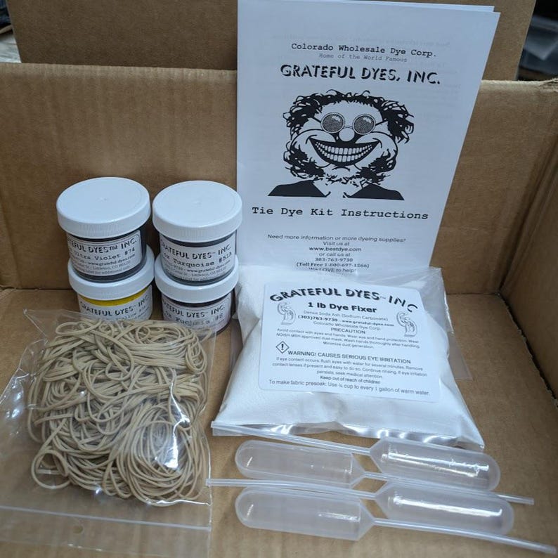 May include: A tie-dye kit with instructions, dye fixers, and various colored dyes in small jars. The kit includes rubber bands and plastic droppers for applying the dye. The packaging features the text "Grateful Dyes, Inc."