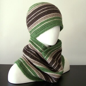 May include: A green and brown striped crocheted hat and matching scarf. The hat is a slouchy style and the scarf is a cowl style.