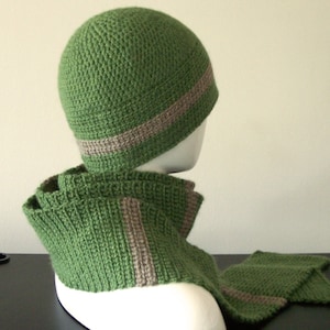 May include: A green crocheted hat with a brown stripe and a matching green crocheted scarf with a brown stripe.