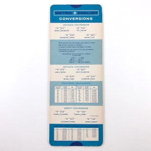 May include: A vintage metric to English conversion chart. The chart is rectangular with a blue border and features conversion tables for distance, weight, and fractional equivalents. The text includes inches, centimeters, feet, meters, miles, kilometers, pounds, ounces, and grams.