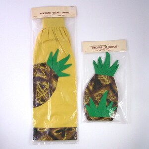 May include: Two packages of pineapple-themed kitchen items. The larger package contains a yellow oven mitt with a brown and green pineapple design. The smaller package contains two brown and green pineapple pot holders.