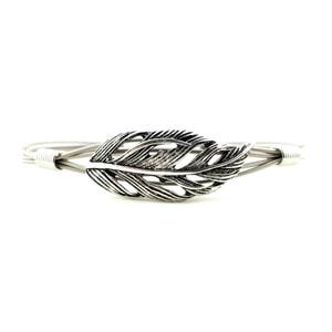 May include: Silver-toned bracelet featuring a detailed feather design. The feather is the focal point, with intricate detailing. The bracelet is made of multiple silver-colored strands, creating a delicate yet sturdy look. A stylish accessory.