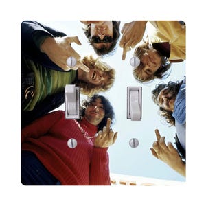 May include: A light switch cover featuring a vintage photograph of five people. The people are looking down at the viewer and giving the middle finger. The cover has two light switch openings and two silver screws.