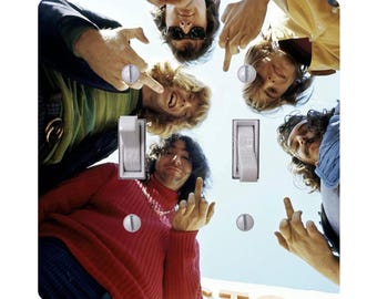 May include: A light switch cover featuring a vintage photograph of five people. The people are looking down at the viewer and giving the middle finger. The cover has two light switch openings and two silver screws.