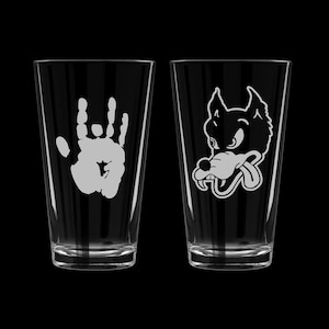 May include: Two clear glass pint glasses with white designs. One glass features a handprint, the other a cartoon wolf's head.