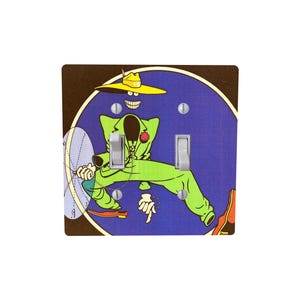 Peut inclure: Un cache-interrupteur d&eacute;coratif avec un personnage de dessin anim&eacute; en costume vert et chapeau jaune sur fond bleu. Le motif comprend une fleur rouge et une horloge. Le cache-interrupteur a deux interrupteurs.