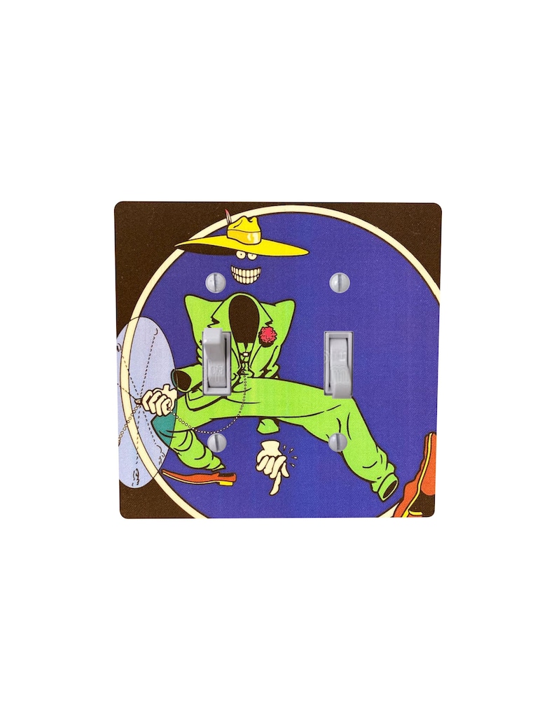 Peut inclure: Un cache-interrupteur d&eacute;coratif avec un personnage de dessin anim&eacute; en costume vert et chapeau jaune sur fond bleu. Le motif comprend une fleur rouge et une horloge. Le cache-interrupteur a deux interrupteurs.